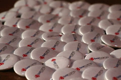 Round BarCamp Ferizaj stickers spread across a table